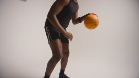 Close-Up-Studio-Shot-Of-Male-Basketball-Player-Dribbling-And-Bouncing-Ball-Against-White-Background-2
